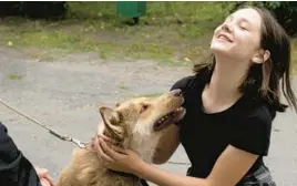  ?? EFREM LUKATSKY/AP ?? A girl plays with a dog on July 19 at a pet shelter in Kyiv, Ukraine. Volunteers opened a shelter to take in family pets shellshock­ed amid the ongoing war with Russia.