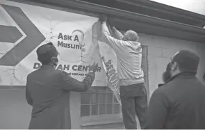  ?? MADDIE MCGARVEY ?? Melvin Burnett hangs a sign at Ask A Muslim headquarte­rs in Columbus. Each year at Ramadan, the organizati­on puts up billboards around the city pointing out commonalit­ies between faith traditions.