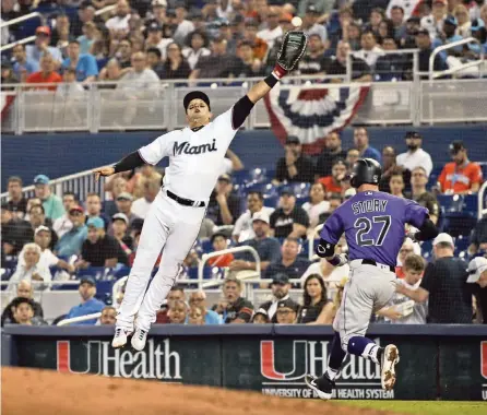  ?? DAVID SANTIAGO dsantiago@miamiheral­d.com ?? Marlins first baseman Martin Prado is unable to catch a poor throw from shortstop Miguel Rojas as the Rockies’ Trevor Story is safe in the fourth inning.