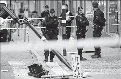  ?? [MARKUS SCHREIBER/THE ASSOCIATED PRESS] ?? Police officers stand next to a destroyed street sign Saturday near the department store Ahlens after an attack in central Stockholm on Friday.