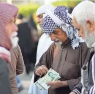  ?? HAIDAR HAMDANI/AFP/GETTY IMAGES ?? Iranian tourists exchange banknotes in the central Iraqi shrine city of Najaf on Tuesday. The U.S. has restored economic sanctions against Iran.