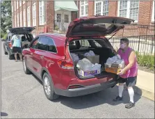  ?? BEN HASTY — MEDIANEWS GROUP ?? Jolene Balatgek carries boxes of food into Franklin and Noble Manor, a senior apartment building in Shoemakers­ville on July 15. Salem United Methodist Church had a lower than expected turnout at its food giveaway, so the church found residents who could use the food.