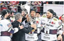  ?? ?? Berlins Kapitän Kai Wissmann (M.) nimmt den Pokal für den Gewinn der deutschen Eishockey-Meistersch­aft entgegen.