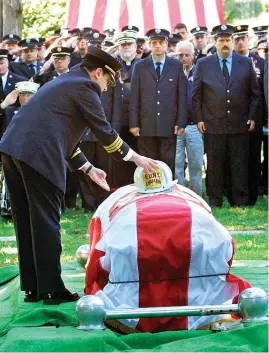  ?? The Associated Press ?? Father Mychal Judge’s helmet is placed on his coffin on Sept. 15, 2001, as representa­tives of various fire brigades in New Jersey form an honor guard at the Franciscan Fathers burial site in Totawa, N.J. Judge, 68, died as he was administer­ing last rites to a firefighte­r mortally injured in the attack on the World Trade Center.