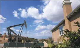  ??  ?? ACTIVISTS are urging Gov. Gavin Newsom to ban fracking and drilling. Above, a pumpjack, or nodding donkey, stands near a home this month in Signal Hill.