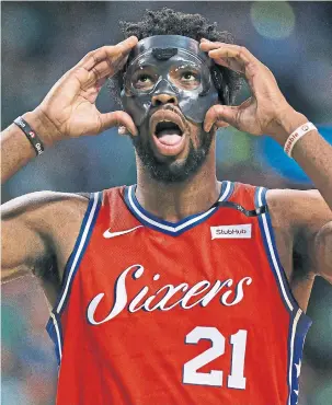  ?? JIM DAVIS/BOSTON GLOBE/GETTY IMAGES ?? Joel Embiid adjusts his face mask during the first half on Monday night in Boston. The Philadelph­ia 76ers centre had 31 points and 13 rebounds in a losing cause. Game 2 is on Thursday.