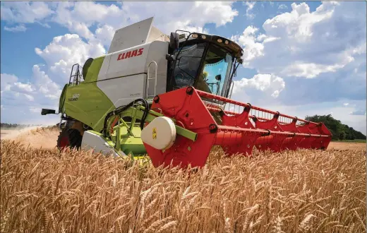  ?? EFREM LUKATSKY/AP ?? A farmer on July 4 collects harvest on his field about 6 miles from the front line in the Dnipropetr­ovsk region, Ukraine. Shipping companies are not rushing to export millions of tons of trapped grain out of Ukraine despite a breakthrou­gh deal to provide safe corridors through the Black Sea, because the waters are mined.