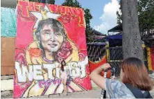  ??  ?? A foreign visitor poses next to a graffiti depiction of Aung San Suu Kyi outside the headquarte­rs of the National League for Democracy party in Yangon. — AFP photo