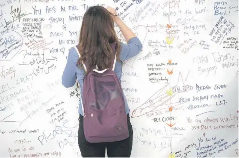  ??  ?? A visitor writes on a banner carrying messages for the passengers of missing Malaysia Airlines flight MH370 at Kuala Lumpur Internatio­nal Airport (KLIA) in Sepang. Planes searching an area where Chinese satellites spotted possible debris from the...