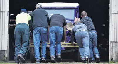  ?? PHOTO: PETER MCINTOSH ?? Helping hands . . . Dunedin Fire Brigade Restoratio­n Society members push a veteran delivery van into the society’s workshop premises yesterday.