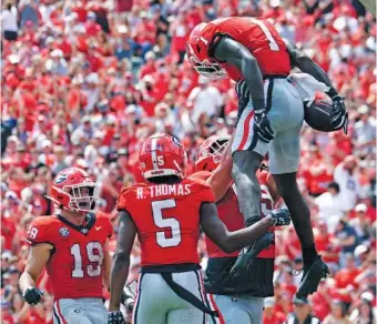  ?? AP PHOTO/JOHN BAZEMORE ?? Georgia receiver Marcus Rosemy-Jacksaint (1) gets a celebrator­y lift from offensive lineman Tate Ratledge after scoring a touchdown during the top-ranked Bulldogs’ 45-3 win over Ball State on Saturday in Athens, Ga.