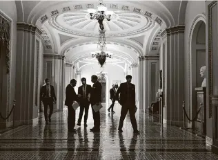  ?? J. Scott Applewhite / Associated Press ?? Congressio­nal staffers wait outside the Senate chamber during a delay in work on the Democrats’ $1.9 trillion relief bill. Democrats are turning to a go-it-alone partisan strategy to pass the package.