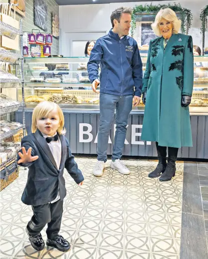  ?? ?? The Queen looks on as 23-month-old Fitz Salmon-corrie plays to the cameras as she visits Knotts Bakery in Lisburn Road, Belfast, as part of a Royal visit to Northern Ireland