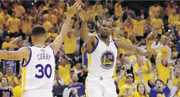  ?? EZRA SHAW/GETTY IMAGES ?? Golden State Warriors guard Stephen Curry and forward Kevin Durant high-five after a play in Game 2 of the NBA Finals on Sunday in Oakland, Calif. In their two post-season games against the Cleveland Cavaliers, Durant is averaging 35.5 points, 11...