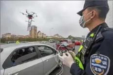  ?? Lai Li/Xinhua via AP ?? A police officer operates a drone carrying a QR code placard Feb. 11 near an expressway toll station in southern China’s Guangdong Province.