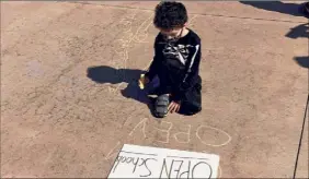  ?? Will Waldron / Times Union ?? Alexander Eldridge, a kindergart­ener from Schenectad­y, writes a chalk message Monday in Albany’s West Capitol Park urging schools to reopen.