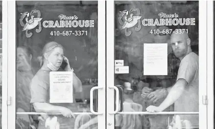  ?? AMY DAVIS/BALTIMORE SUN ?? Vince Meyer, right, with his mother at left, watches the protesters outside his restaurant, Vince’s Crab House, in Middle River