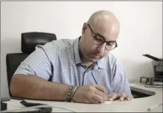  ?? AP PHOTO/NARIMAN ELMOFTY ?? Mohamed Zaree, human rights advocate and legal scholar, writes on a card after an interview with The Associated Press in Cairo, Egypt, on Tuesday. Ten of the world’s leading human rights organizati­ons have selected Zaree for the prestigiou­s Martin...