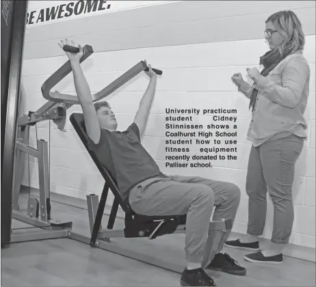  ??  ?? University practicum student Cidney Stinnissen shows a Coalhurst High School student how to use fitness equipment recently donated to the Palliser school.