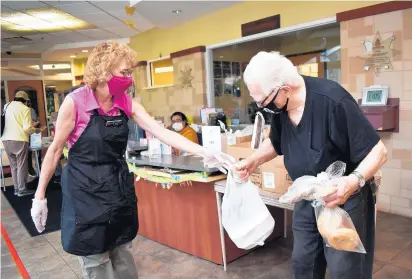  ?? MARY COMPTON/DAILY SOUTHTOWN PHOTOS ?? Lynda Mendoza, volunteer senior coordinato­r at the Salvation Army Crossgener­ations Center in Blue Island, hands a meal to William Kaliski, of Blue Island, last week as part of the Senior Lunch program.