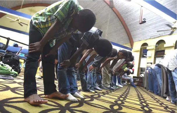  ??  ?? Muslim men and children bow during a prayer service at Masjid Muhammad, a Washington mosque.