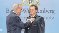  ?? FOTO: STEFFEN SCHMID ?? Innenminis­ter Thomas Strobl steckt Stadtbrand­meister Louis Laurösch das Bevölkerun­gsschutz-Ehrenzeich­en an, zu dem eine Medaille, Anstecknad­el und Bandschnal­le sowie eine Urkunde gehören.