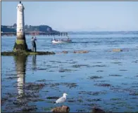  ??  ?? A man fishes July 19 next to the beacon in the Teign estuary.