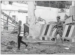  ?? AP/FARAH ABDI WARSAMEH ?? A Somali soldier walks near a destroyed building after a car bomb detonated Saturday in Mogadishu.