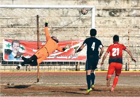  ?? AFP ?? A goalkeeper dives to make a save during the Syrian league football match between derby rivals Al-Ittihad (red) and Al-Hurriya, in Syria’s northern city of Aleppo.