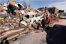  ?? ?? People survey damage from a tornado in Mayfield, Ky., one year ago. The holiday season tragedy killed 81 people in Kentucky and turned buildings into mounds of rubble.