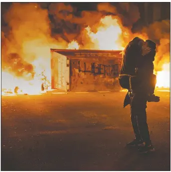  ?? (AP/Emilio Morenatti) ?? A couple kiss in front of a barricade set on fire by demonstrat­ors during clashes with police in Barcelona.