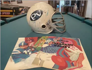  ?? PHOTOS BY JUSTIN COUCHOT — ENTERPRISE-RECORD ?? ABOVE: Former Pleasant Valley football player Larry Stephenson, class of 1971, displays his helmet and the programs from the Chico High against Pleasant Valley games in 1969and 1970on the pool table of Stephenson’s home on Monday in Chico. Chico High and Pleasant Valley played against each other for the first time in 1968, 1969and 1970before the Almond Bowl was establishe­d in 1971. BELOW: The Almond Bowl winner plaque, left, and a trophy with the names of Chico High’s Almond Bowl Most Valuable Player recipients are shown inside the Athletic Administra­tion building at Chico High.