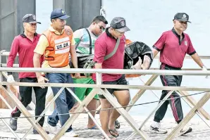  ?? — Gambar AFP ?? ANGGOTA penyelamat Thai mengangkat mayat pelancong yang mati lemas selepas sebuah bot karam di luar pantai pulau peranginan Phuket, Thailand, semalam.