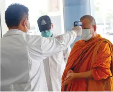  ?? PATTARAPON­G CHATPATTAR­ASILL ?? A monk is checked for signs of fever before entering the Mor Chit main bus terminal.
