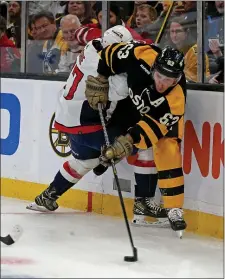  ?? STUART CAHILL — BOSTON HERALD ?? Boston Bruins left wing Brad Marchand (63) dishes off the puck as he is tied up by Washington Capitals right wing T.J. Oshie during Boston’s 2-1 loss on Saturday.