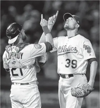  ?? Ben Margot / Associated Press ?? Catcher Jonathan Lucroy, left, and Blake Treinen of the A’s celebrate the team’s 3-2 win over the Mariners on Tuesday. Oakland can take over the AL West lead with a three-game series sweep.