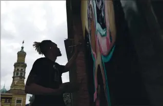  ?? KELLY WILKINSON — THE INDIANAPOL­IS STAR VIA AP ?? Fitz Young paints a mural on a business on Massachuse­tts Avenue on June 8.