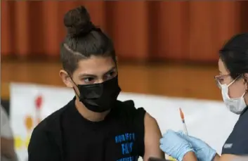  ?? Mark Lennihan/Associated Press ?? Jesah Hernandez, a high school student, gets the Pfizer COVID-19 vaccine from Aylara Geldyeva on Tuesday in New York.