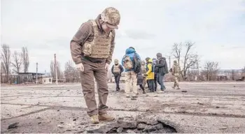  ?? OLEKSANDR RATUSHNIAK/AP ?? A Ukrainian soldier looks at a hole from a shell that was fired Saturday in Novoluhans­ke, Ukraine.