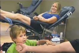  ?? Darrell Sapp/Post-Gazette ?? Lucas Goeller, 4, plays with bandages on his father’s arm as Rick Goeller and Lucas’ mother, Jess Goeller, give blood Monday at the Central Blood Bank Community Donor Center in Harmar. His parents are donating blood hoping to encourage others to do the...