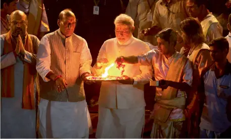  ?? — AP ?? BJP leader Narendra Modi, set to be India’s new Prime Minister, performs Ganga aarti with BJP president Rajnath Singh while Mr Modi’s top aide, Mr Amit Shah, folds his hands in prayer at Dashashwam­edh Ghat on the Ganga in Varanasi on Saturday.