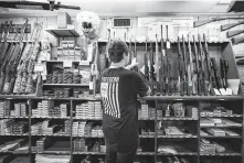  ?? Erin Schaff / New York Times ?? An employee handles a rifle for sale at Clark Brothers Gun Shop in Warrenton, Va. Firearms sales have dropped during the Trump presidency.