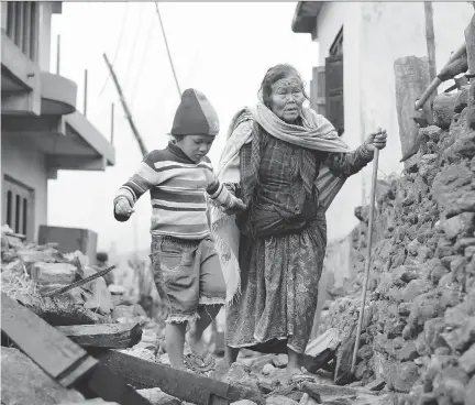  ?? WALLY SANTANA/THE ASSOCIATED PRESS ?? Jagot Kumari Rana, 79, is led through the rubble of collapsed homes by her grandson, Sogat Rana, 7, in Paslang village near the epicentre of Saturday’s massive earthquake in the Gorkha District of Nepal on Tuesday.