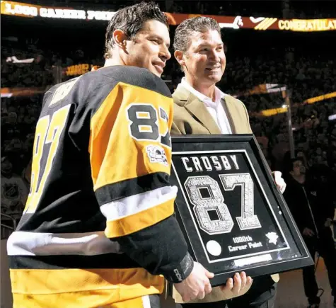  ?? Matt Freed/Post-Gazette ?? Owner Mario Lemieux presents captain Sidney Crosby with a commemorat­ive plaque Sunday at PPG Paints Arena celebratin­g Crosby’s 1,000th career point, which he scored last week against the Winnipeg Jets.
