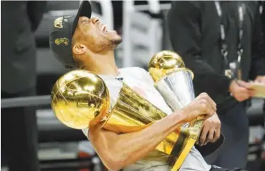  ?? Associated Press ?? ↑
Milwaukee Bucks Giannis Antetokoun­mpo celebrates while holding the NBA Championsh­ip trophy and the MVP trophy.