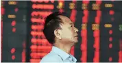  ?? PHOTO: REUTERS ?? An investor stands at a brokerage house, near an electronic board filled with red figures indicating rising prices, in Fuyang, China on Tuesday
