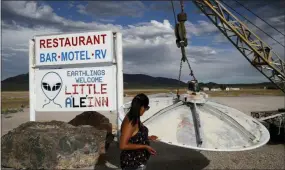  ?? AP PHOTO/JOHN LOCHER ?? Grace Capati looks at a UFO display outside of the Little A’Le’Inn, in Rachel, Nev., the closest town to Area 51. The U.S. Air Force has warned people against participat­ing in an internet joke suggesting a large crowd of people “storm Area 51,” the top-secret Cold War test site in the Nevada desert.