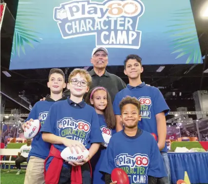  ?? DANIEL A. VARELA dvarela@miamiheral­d.com ?? Mexican-American NFL Hall of Famer Anthony Munoz stands with camp MVPs following the NFL Play 60 Character Camp at the Super Bowl Experience this week at the Miami Beach Convention Center. Munoz started the camps to promote interest in football with Hispanic youth.