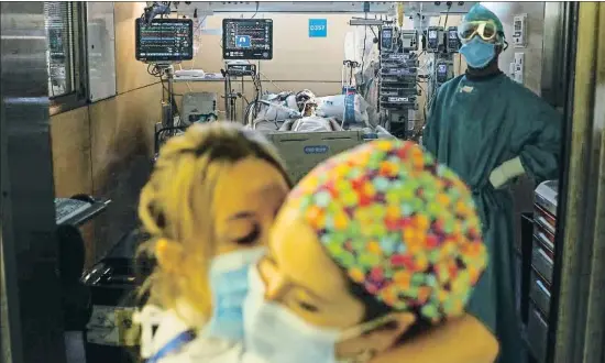  ?? ÀLEX GARCIA ?? Dos enfermeras se abrazan en la puerta de un box ocupado por un paciente muy grave de 24 años en una imagen del pasado día 19