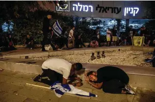  ?? Heidi Levine / Associated Press ?? Jewish nationalis­t demonstrat­ors take cover in Ramla as rockets are fired from the Gaza Strip toward central Israel. The protesters were making a show of strength in a mostly Arab neighborho­od.